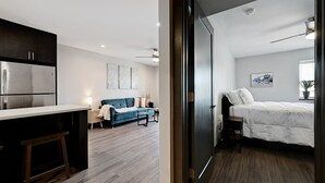 Um apartamento moderno com cozinha, sala de estar com sofá e mesa de centro, e quarto com cama e janela.