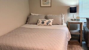 A bedroom with a large bed, a nightstand, a lamp, and a framed picture on the wall. - Studio Unit in Kouts/Valparaiso 3 (Kouts)