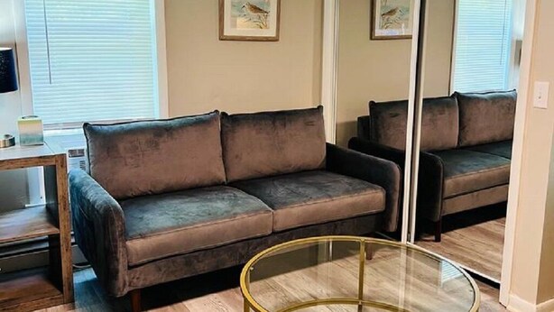 A living room with a brown sofa, a glass coffee table, and a sliding door closet. - Studio Unit in Kouts/Valparaiso 3 (Kouts)