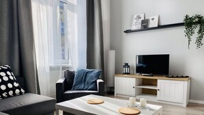 Ein modernes Wohnzimmer mit einer Couch, einem Couchtisch, einem Fernseher und einem Bücherregal.