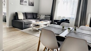 Ein modernes Wohnzimmer mit grauem Sofa, weißem Couchtisch und Essbereich mit Stühlen und Tisch.