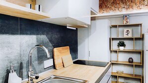 A modern kitchen with a stainless steel sink, wooden countertop, and a brick wall above.