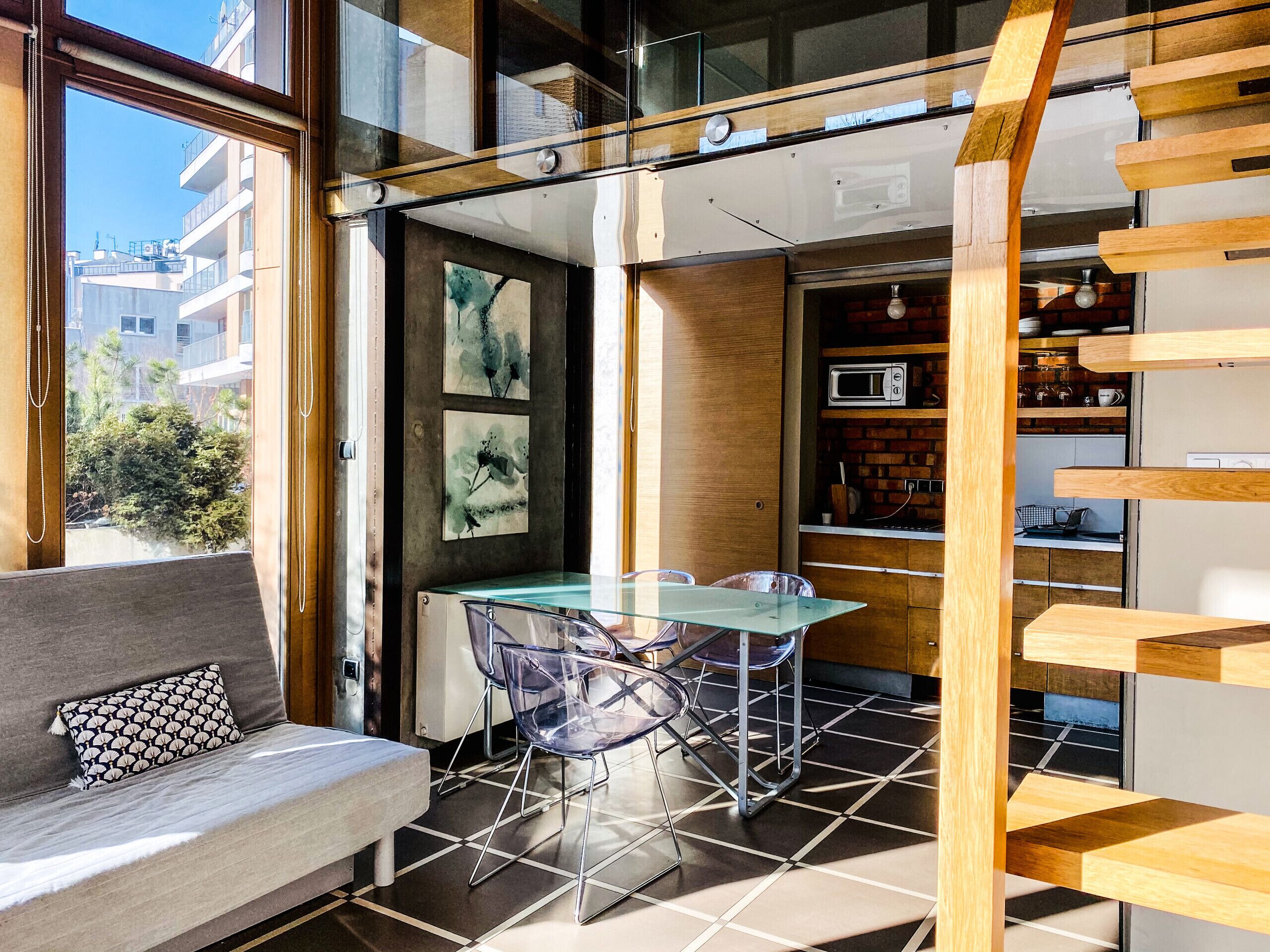 Une cuisine moderne avec une table à manger en verre, des chaises transparentes et un four à micro-ondes encastré.