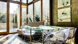 Un espace de salle à manger moderne avec une table et des chaises en verre, de grandes fenêtres et des œuvres d’art accrochées aux murs.