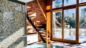 Un intérieur moderne avec une table en verre, un mur en briques et un escalier menant à un espace extérieur.