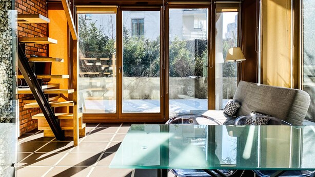 Un intérieur moderne avec une table en verre, un canapé et un escalier doté d’étagères en bois.