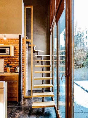 A modern kitchen with a brick wall, a wooden countertop, and a built-in oven. - Beautiful Apartment with Patio & A/C, Old Town III, Zwierzyniecka (Kraków)