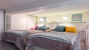 Ein Schlafzimmer mit zwei Betten, einem Kleiderschrank, einem Nachttisch, einem Spiegel und einem Wandregal mit Dekoration.