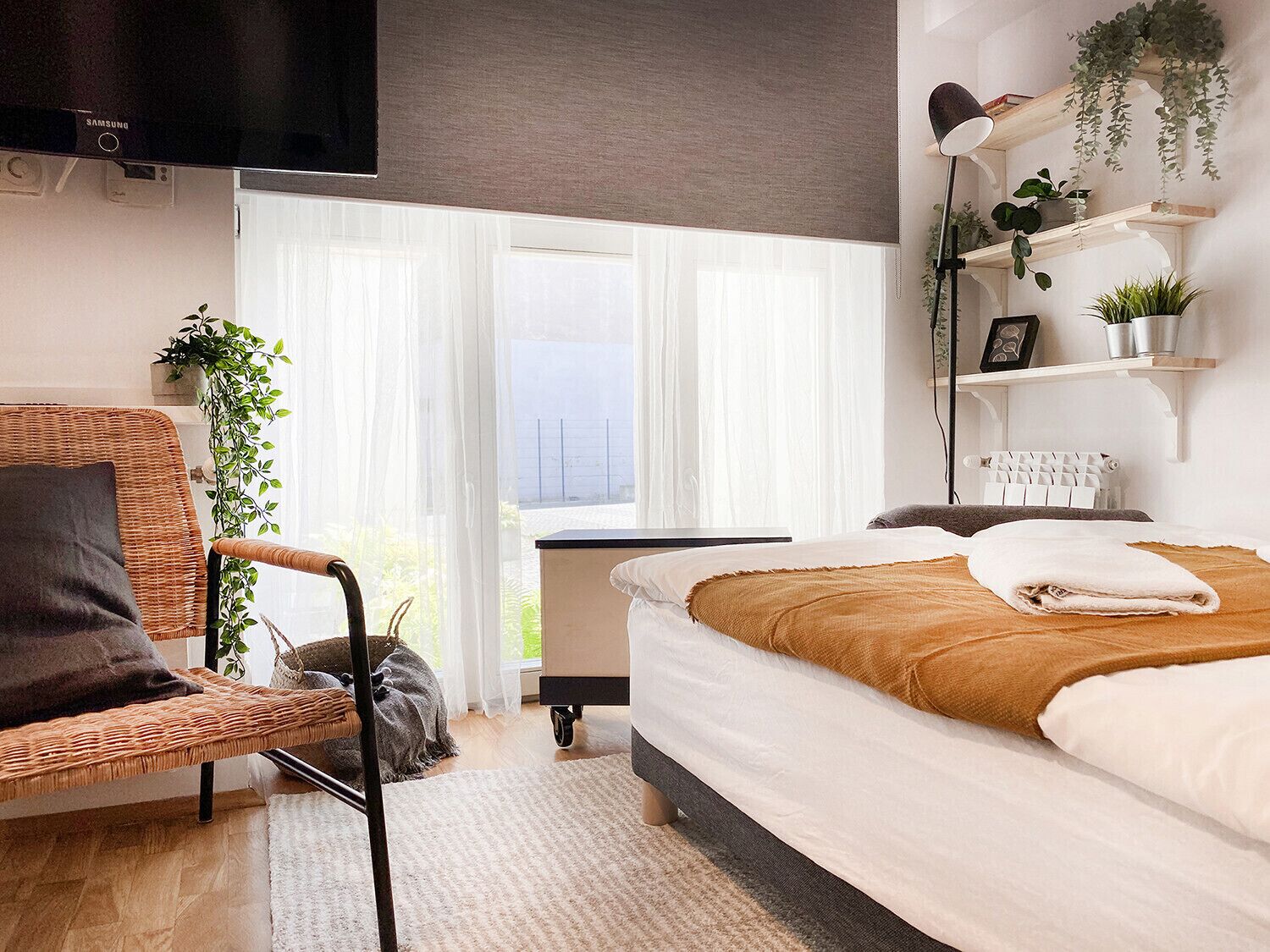 Un dormitorio moderno con cama, una silla, un escritorio y una ventana con cortinas.