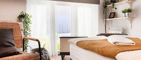 Un dormitorio moderno con cama, una silla, un escritorio y una ventana con cortinas.