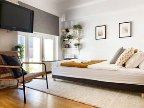 A modern bedroom with a bed, a chair, a TV, and a window. - Łobzowska 22/20 (Kraków)
