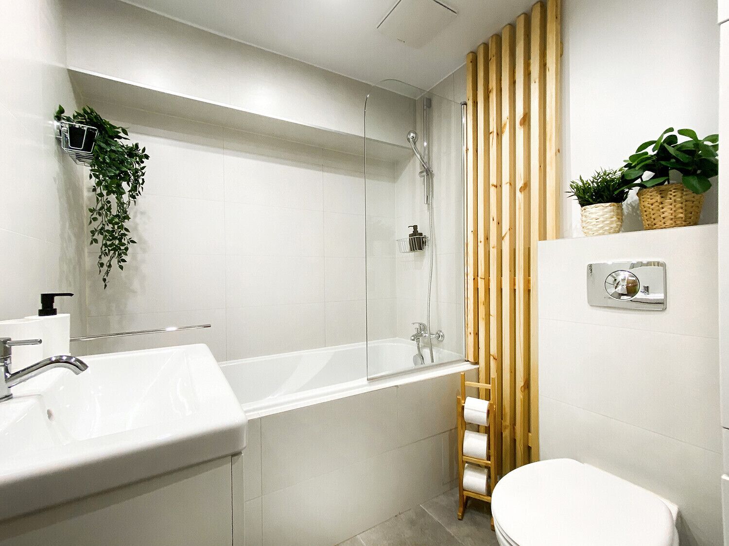 Une salle de bain moderne avec un lavabo blanc, une douche à parois de verre et un mur recouvert de panneaux en bois.