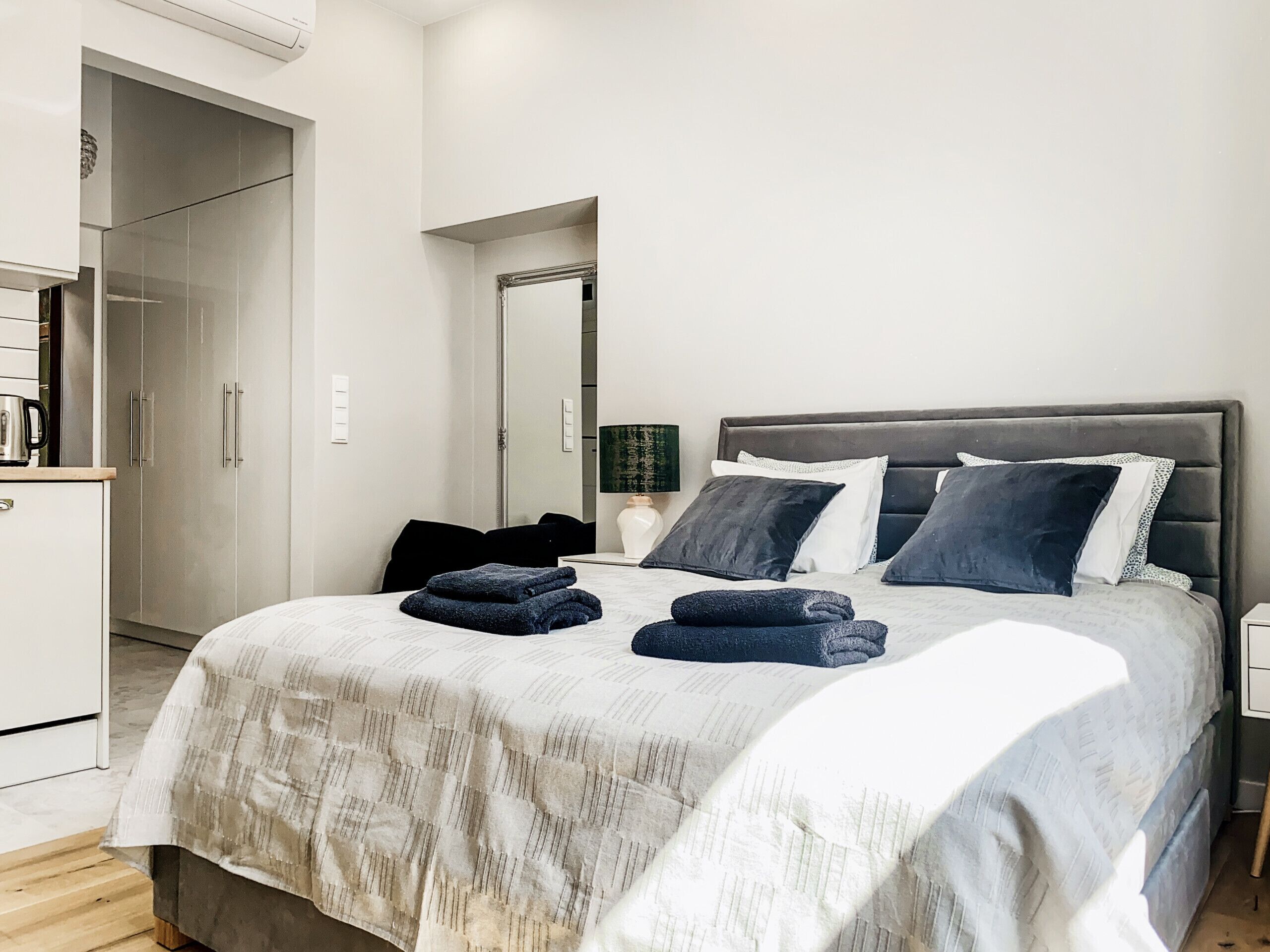 Ein modernes Schlafzimmer mit einem großen Bett, einem Kleiderschrank und einem Spiegel.