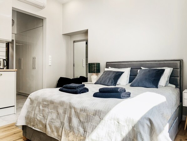 A modern bedroom with a large bed, a wardrobe, and a mirror.