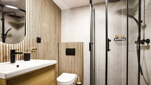 A modern bathroom with a wooden vanity, a toilet, a glass shower enclosure, and a black sink.