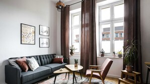 A modern living room with a sofa, coffee table, and chair, a rug, and a window with curtains.