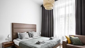 Ett modernt sovrum med en stor säng, sängbord, en soffa och en hängande lampa.