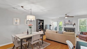 A modern living room with a fireplace, a dining area with a table and chairs, and a sofa.