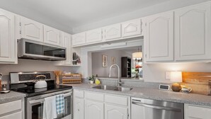 A modern kitchen with white cabinetry, stainless steel appliances, and a granite countertop.