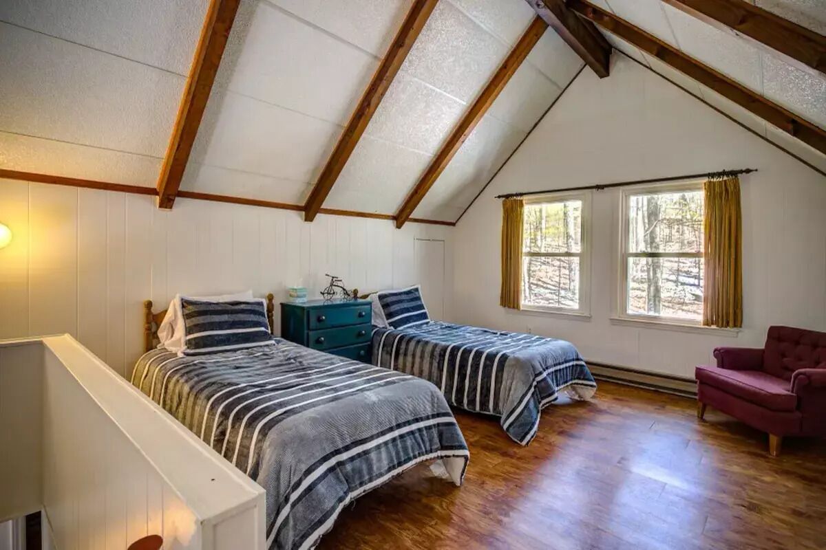 Een slaapkamer met twee bedden, een kaptafel, een stoel en een raam met gordijnen.