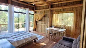 A wooden cabin with a bed, a table, and a couch. - YAAHOO ECOLODGE (Bocaina do Sul)