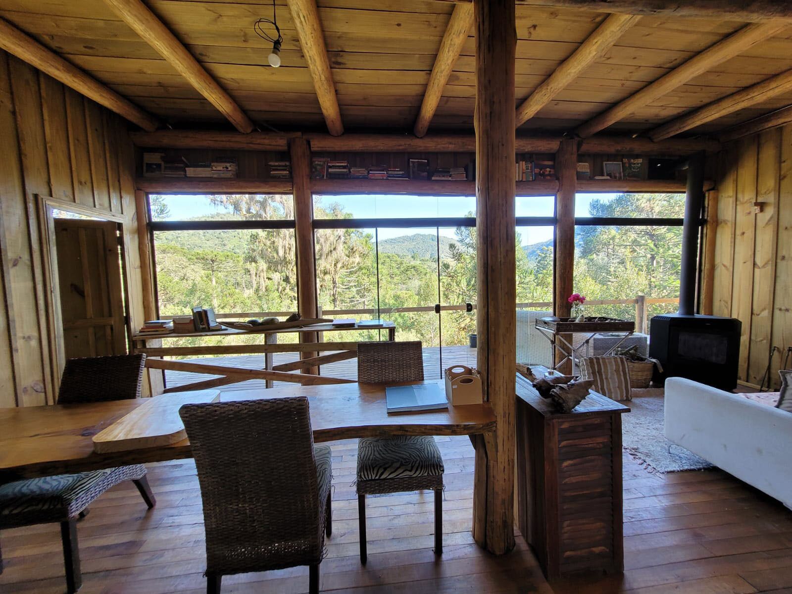 A rustic cabin interior with wooden floors, a dining area, a sofa, and a television.