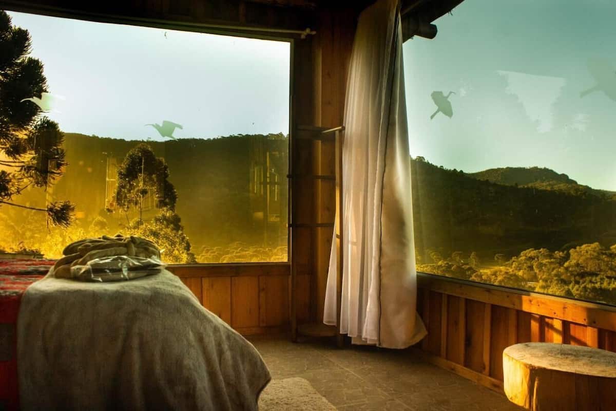 Una habitación con un ventanal grande que da a una zona boscosa.