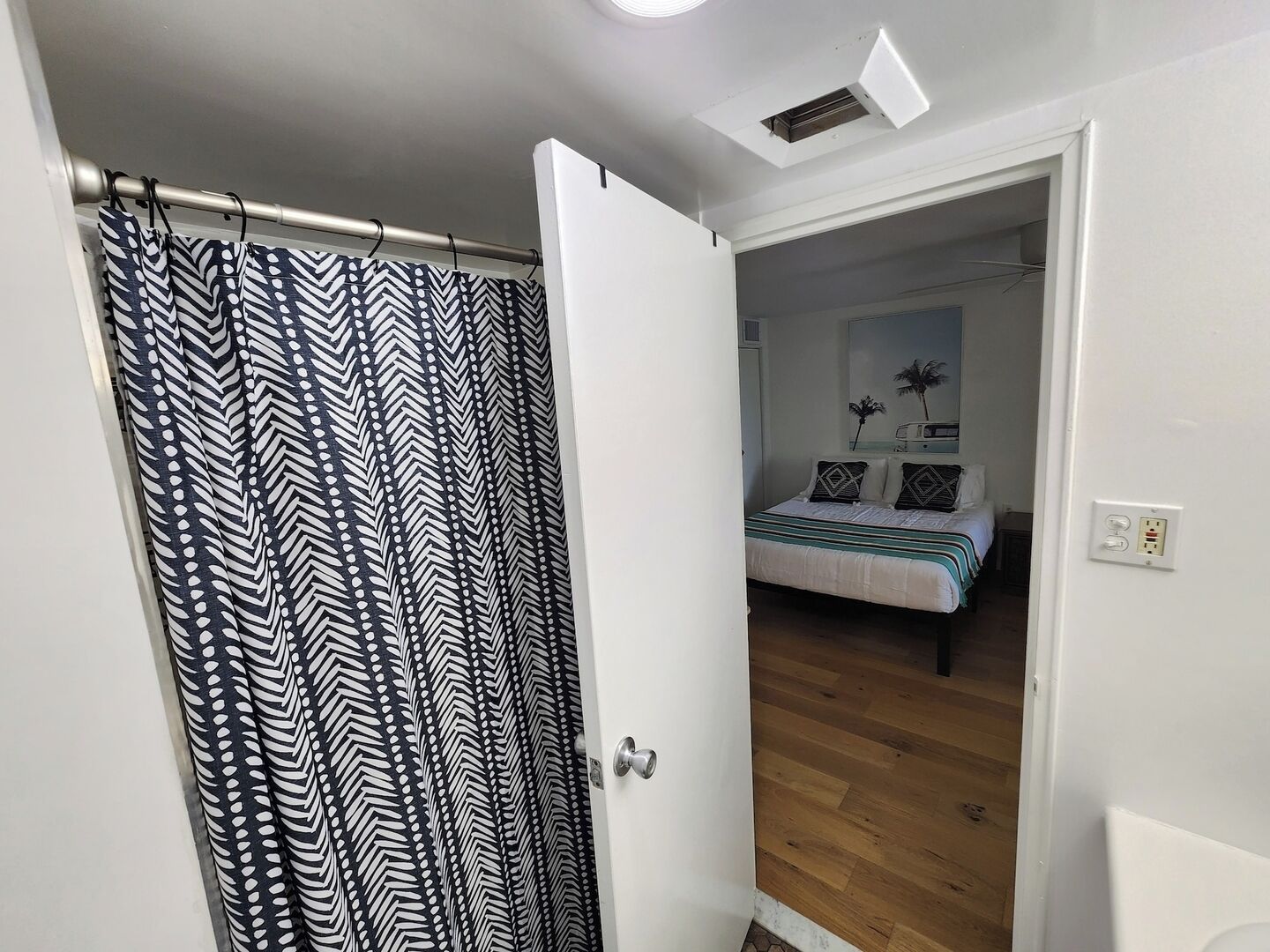 A bedroom with a bed, a nightstand, and a mirror.