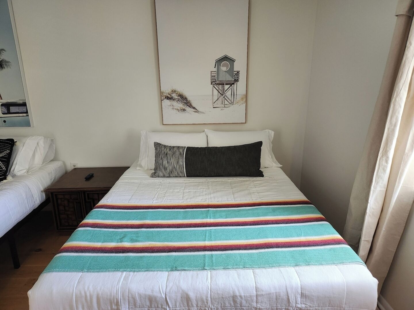 Een slaapkamer met een bed, een nachtkastje, een stoel en een schilderij aan de muur.
