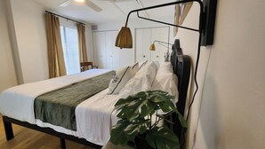 Un dormitorio moderno con una cama, un ventilador de techo, una lámpara de pared y una planta en maceta.