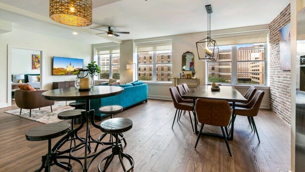Una sala de estar moderna con comedor, ventanas amplias y vista a la ciudad.