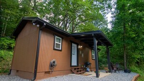 A small wooden cabin with a covered porch, a door, and a window. - The Lil House with Balcony (Robbinsville)