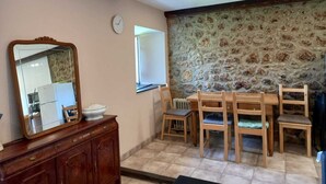 A dining area with a stone wall, wooden furniture, and a large mirror. - Ca Bastiana (Sevares)
