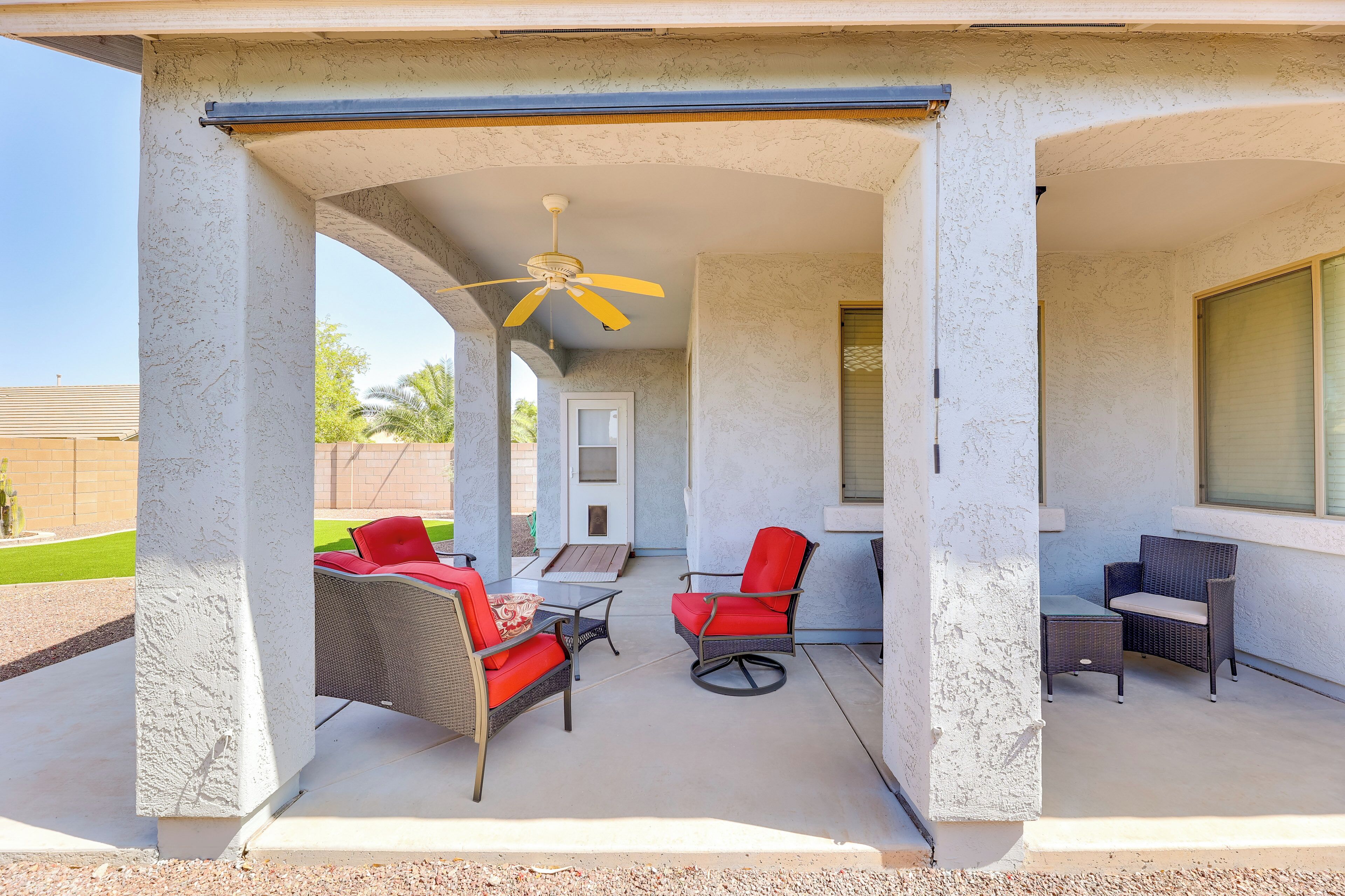 A covered patio with outdoor furniture, a ceiling fan, and a view of the backyard.