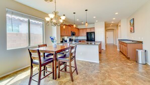 A spacious kitchen with wooden cabinets, a central island, and pendant lighting. - Near Parks & Golf: Maricopa Home w/ Covered Patio! (Maricopa)