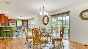 Un coin repas avec une table en verre entourée de chaises décoratives, un lustre et un grand miroir au mur.