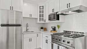A modern kitchen with white cabinets, stainless steel appliances, and a built-in microwave.