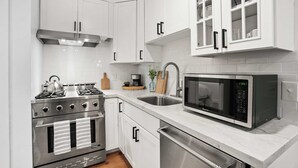A modern kitchen with white cabinetry, stainless steel appliances, a microwave, and a gas stove. - Manresa Surf House 1 bedroom Sleeps 4 unit #2 (La Selva Beach)