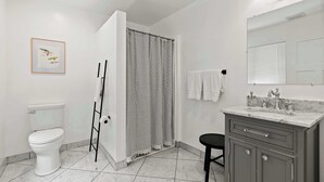 A bathroom with a toilet, shower curtain, vanity with a mirror, and a framed picture on the wall. - Manresa Surf House 1 bedroom Sleeps 4 unit #2 (La Selva Beach)