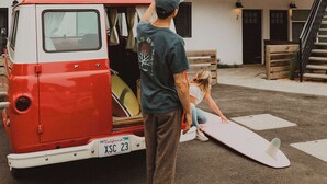 Uma carrinha vermelha e branca estacionada em frente a um edifício moderno de dois andares com varanda.