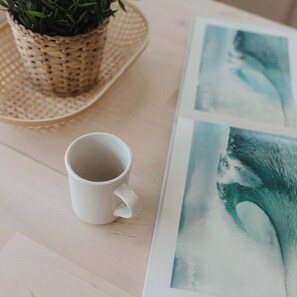 Eine weiße Tasse auf einem Tisch mit Untersetzer aus Bändern und einer Blumentopf-Pflanze.