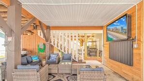 A covered outdoor seating area with wicker furniture and a view of a cityscape through a large window. - Beautiful 5BR Beach House Ocean Lakes with Ocean and Lake Views (Myrtle Beach)