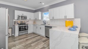 A modern kitchen with white cabinetry, a microwave, oven, and dishwasher. - Beautiful 5BR Beach House Ocean Lakes with Ocean and Lake Views (Myrtle Beach)