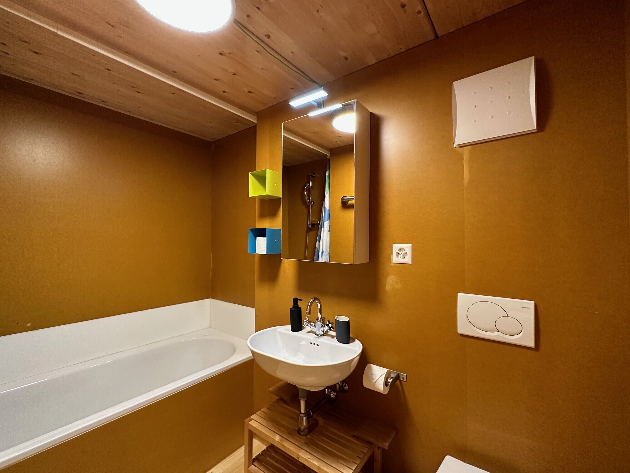 Un baño con una bañera blanca, un lavamanos con espejo y un banco de madera.