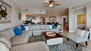 A spacious living room with a large sectional sofa, a coffee table, and a dining area in the background. - San Remo by Southern Vacation Rentals (Santa Rosa Beach)