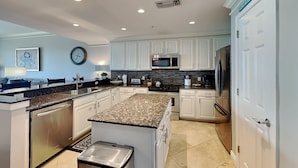 A modern kitchen with white cabinets, granite countertops, stainless steel appliances, and a clock on the wall. - San Remo by Southern Vacation Rentals (Santa Rosa Beach)
