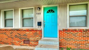A house with a blue door, numbered 7305, and a brick exterior.