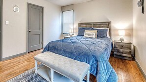 A bedroom with a bed, a bench, a nightstand, a ceiling fan, and a window.