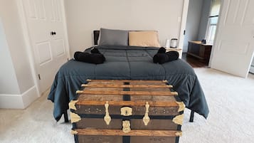 Un dormitorio con una cama, un baúl de madera grande y una mesita de noche.