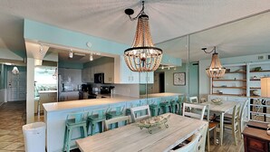 A spacious kitchen with a central island, modern appliances, and a dining area with a wooden table and chairs. - Regency Towers by Resort Collection (Panama City Beach)